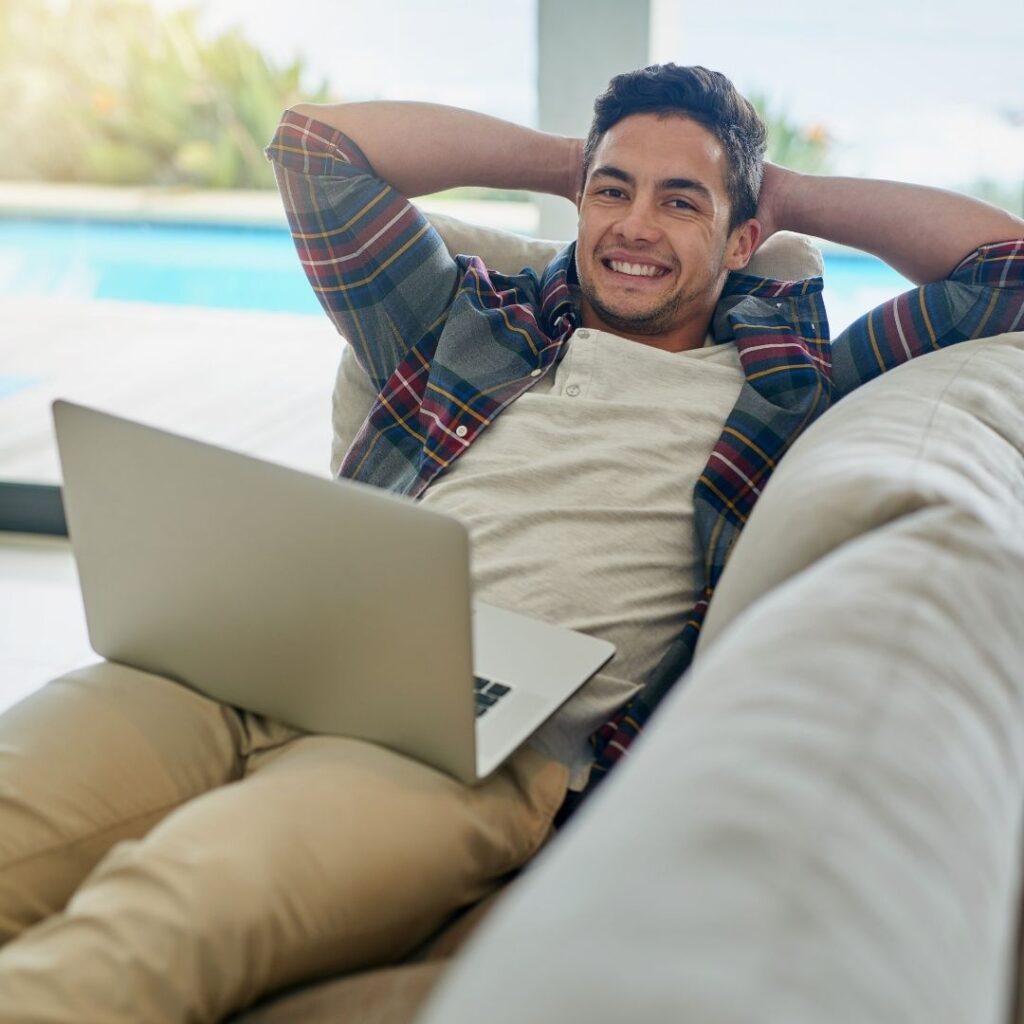 a man reclines on aa couch with a computer on his lap
