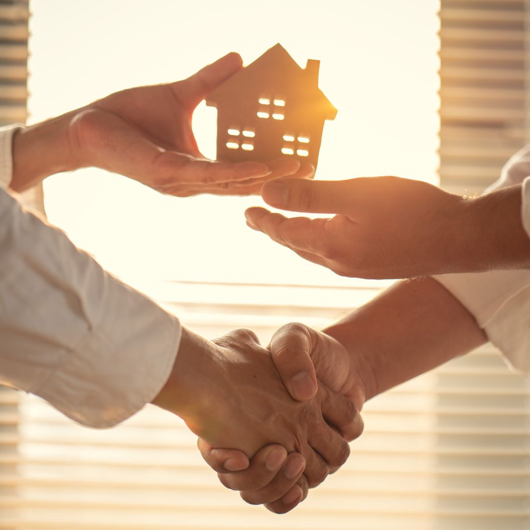 shaking hands holding a wood house