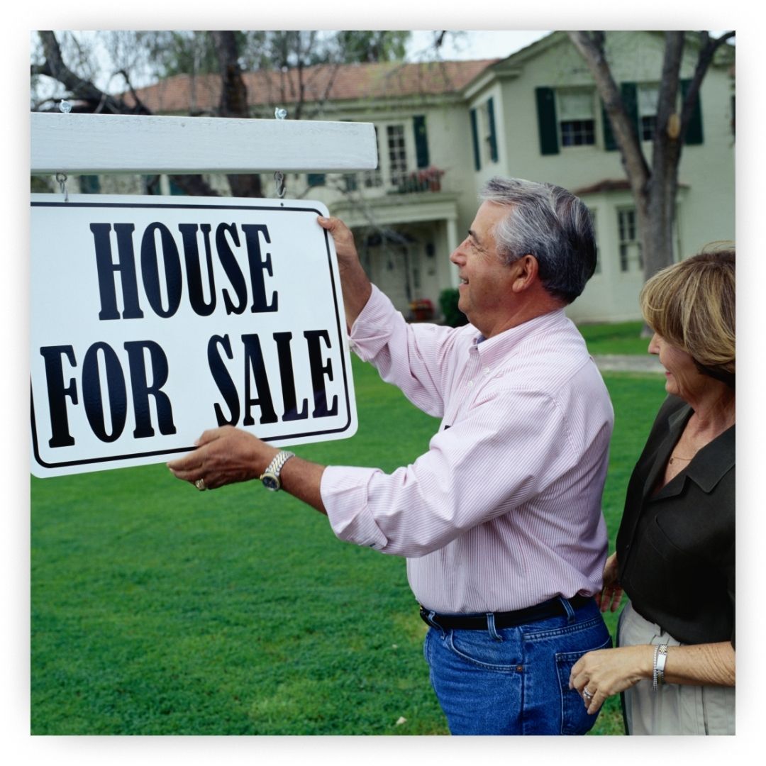 man hanging "house for sale" sign