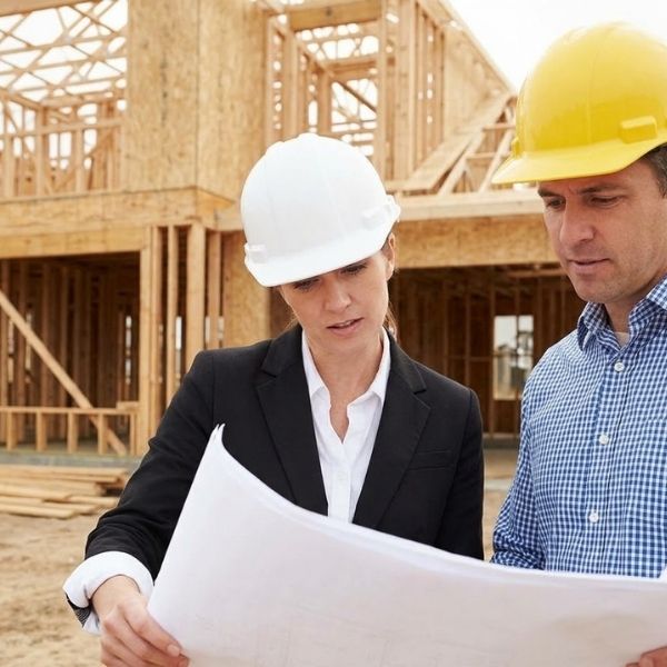 An architect and developer review blueprints while standing on a residential construction site